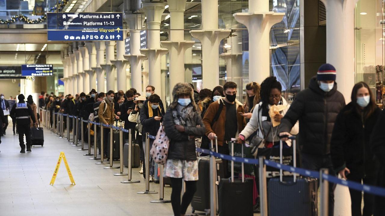 Reisende mit Mund-Nasen-Bedeckungen warten im Londoner Bahnhof St. Pancras in einer Schlange, um den letzten Zug nach Paris zu nehmen.