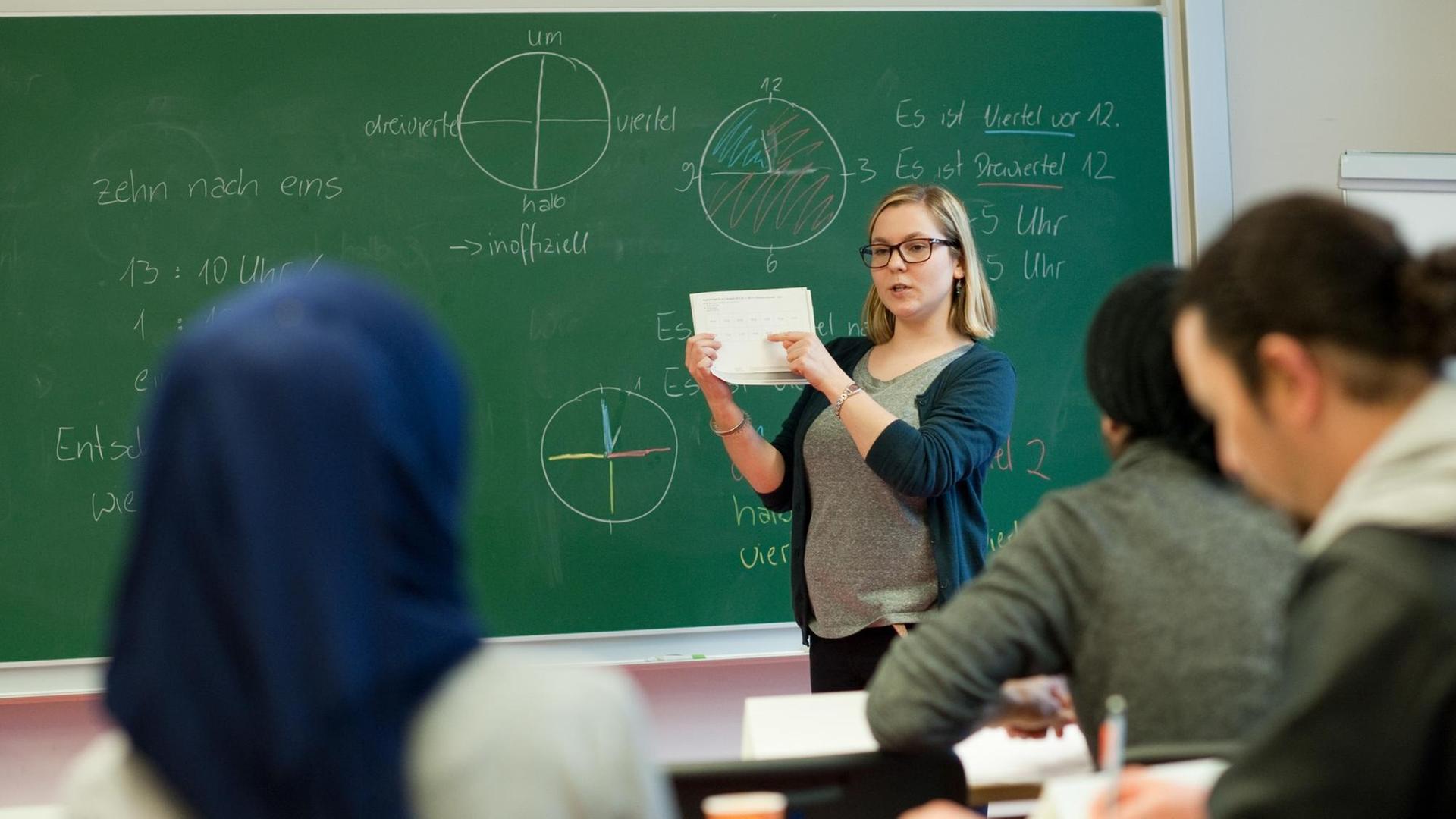 Leiterin des ersten Intensivsprachkurses, Claudia Hubatsch, steht in einem Hörsaal der Uni Potsdam vor einer Tafel vor Schülern und hält ein Blatt Papier in der Hand. Leiterin des ersten Intensivsprachkurses, Claudia Hubatsch, steht in einem Hörsaal der Uni Potsdam vor einer Tafel vor Schülern und hält ein Blatt Papier in der Hand.