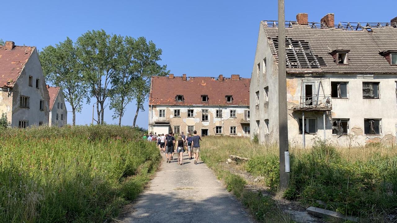 Auf einem Weg zwischen den zerfallenen Häusern ist weit hinten eine Touristengruppe zu sehen. Auf einem Weg zwischen den zerfallenen Häusern ist weit hinten eine Touristengruppe zu sehen.