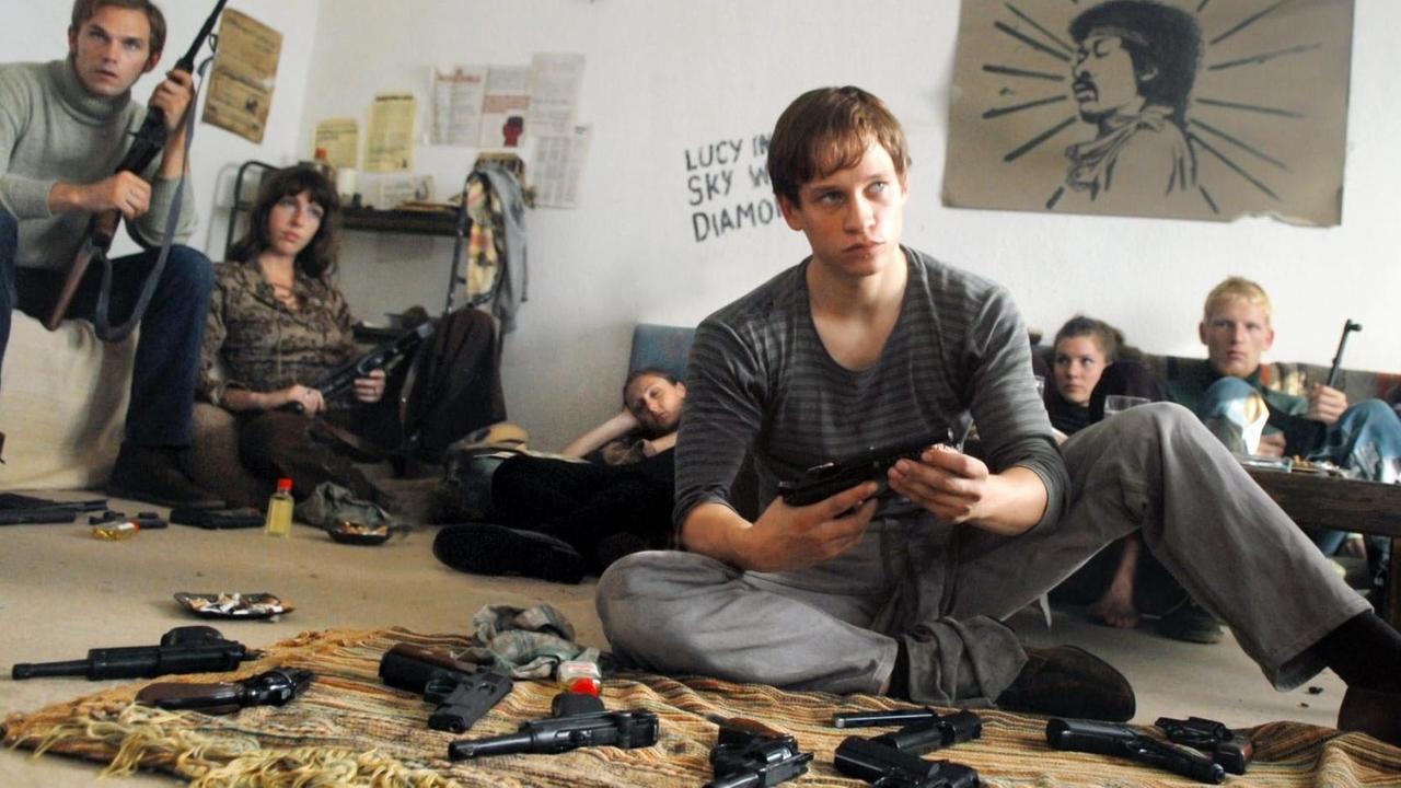 Szene aus dem Film "Der Baader Meinhof Komplex" aus dem Jahr 2008: Junge Männer und Frauen sitzen in einem Zimmer auf dem Boden, im Vordergrund Waffen auf einem Stück Stoff. Szene aus dem Film "Der Baader Meinhof Komplex" aus dem Jahr 2008: Junge Männer und Frauen sitzen in einem Zimmer auf dem Boden, im Vordergrund Waffen auf einem Stück Stoff.