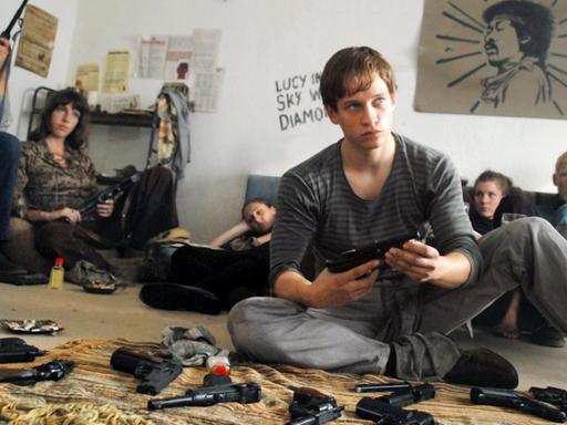Szene aus dem Film "Der Baader Meinhof Komplex" aus dem Jahr 2008: Junge Männer und Frauen sitzen in einem Zimmer auf dem Boden, im Vordergrund Waffen auf einem Stück Stoff.