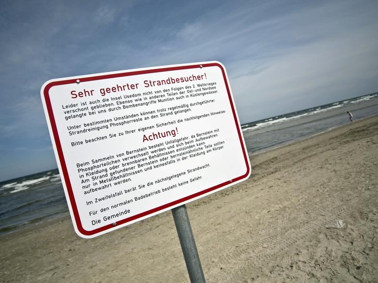 Ein Schild mit Warnhinweisen vor phosphorhaltiger Weltkriegsmunition steht am Strand von Karlshagen auf Usedom.