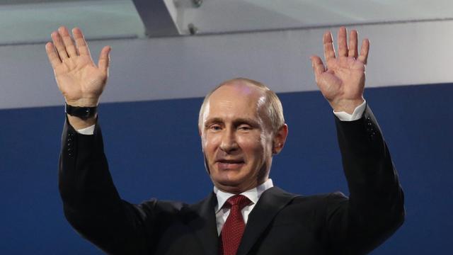Wladimir Putin im Anzug winkt mit beiden Händen
