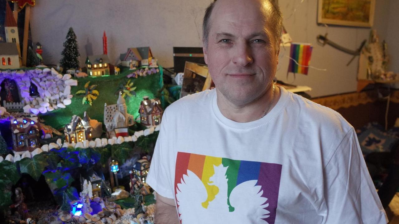 Bild eines Mannes mit Regebogen-T-Shirt in seiner Wohnung Bild eines Mannes mit Regebogen-T-Shirt in seiner Wohnung