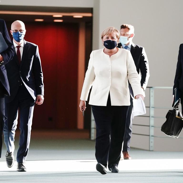 Bundeskanzlerin Angela Merkel (CDU, Mitte), Bayerns Ministerpräsident Markus Söder (CSU, l.), Hamburgs Erster Bürgermeister Peter Tschentscher (SPD, 2.v.l.) und Regierungssprecher Steffen Seibert (r) gehen zur Pressekonferenz.