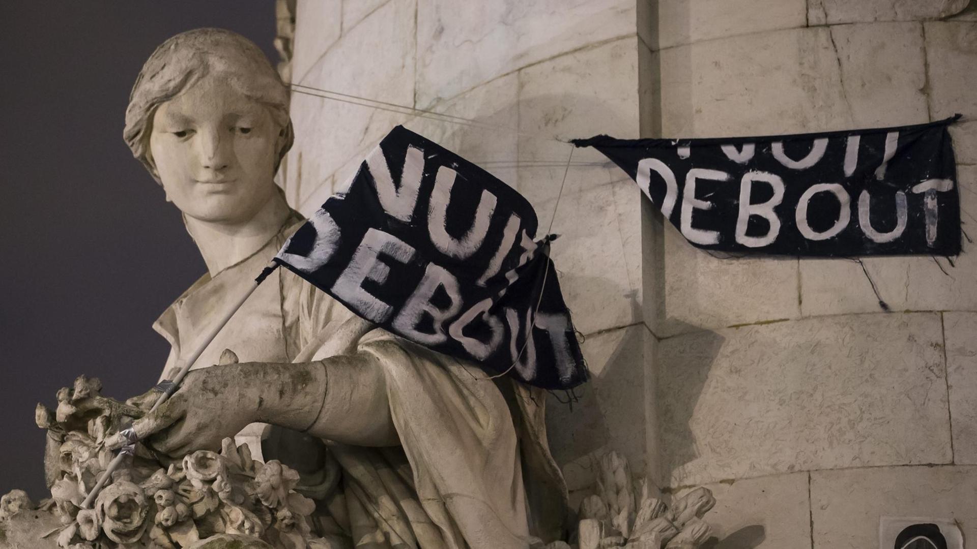 Ein Transparent mit dem Schriftzug "'La Nuit Debout" hängt über einer Statue am Place de la Republique in Paris.