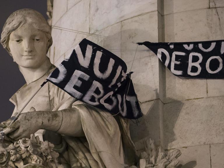 Ein Transparent mit dem Schriftzug "'La Nuit Debout" hängt über einer Statue am Place de la Republique in Paris