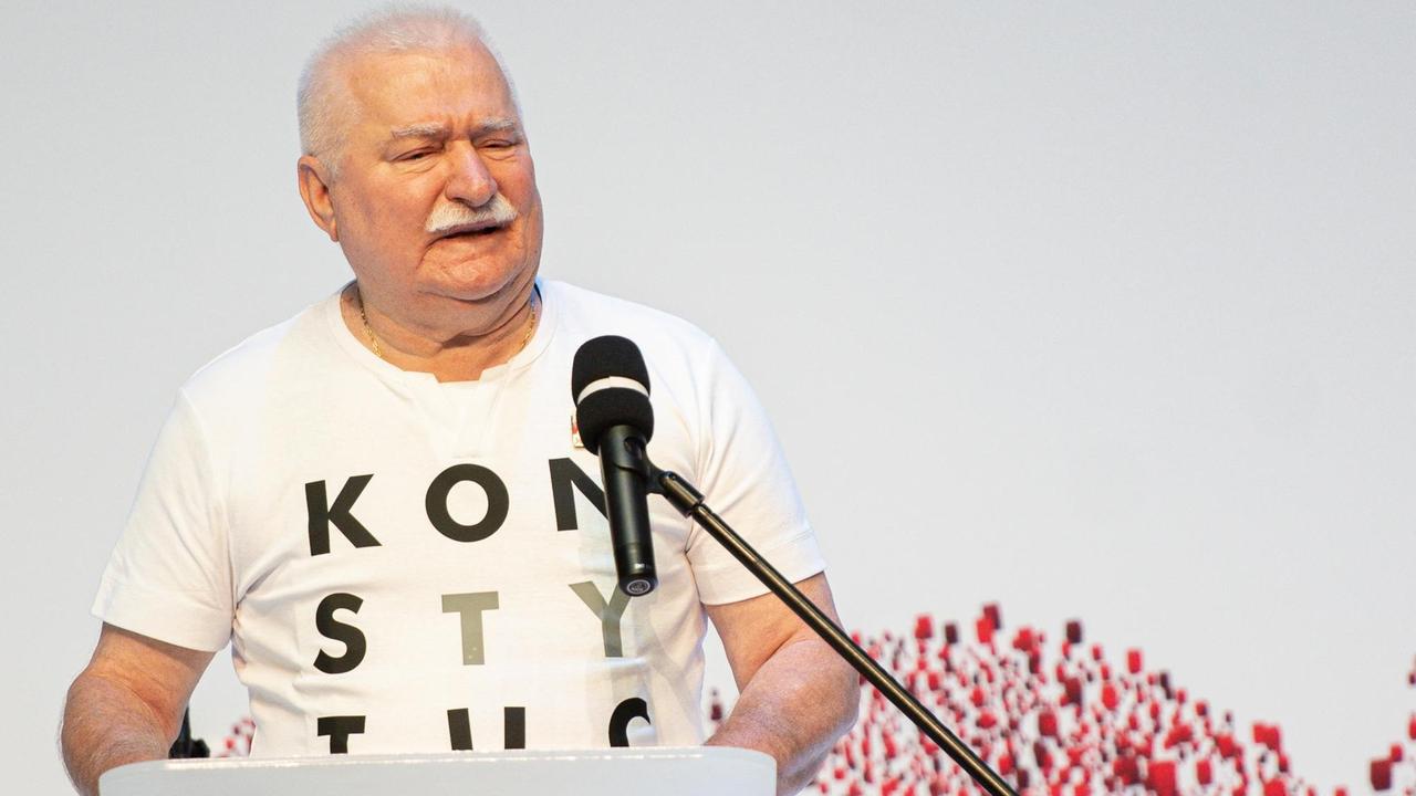 Lech Wałęsa steht im T-Shirt vor einem Mikrofon. 