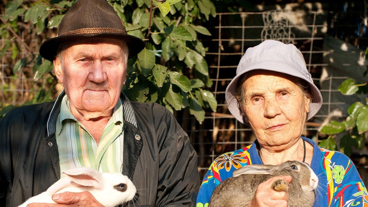 Ein älteres Ehepaar mit je einem Kaninchen im Arm Ein älteres Ehepaar mit je einem Kaninchen im Arm