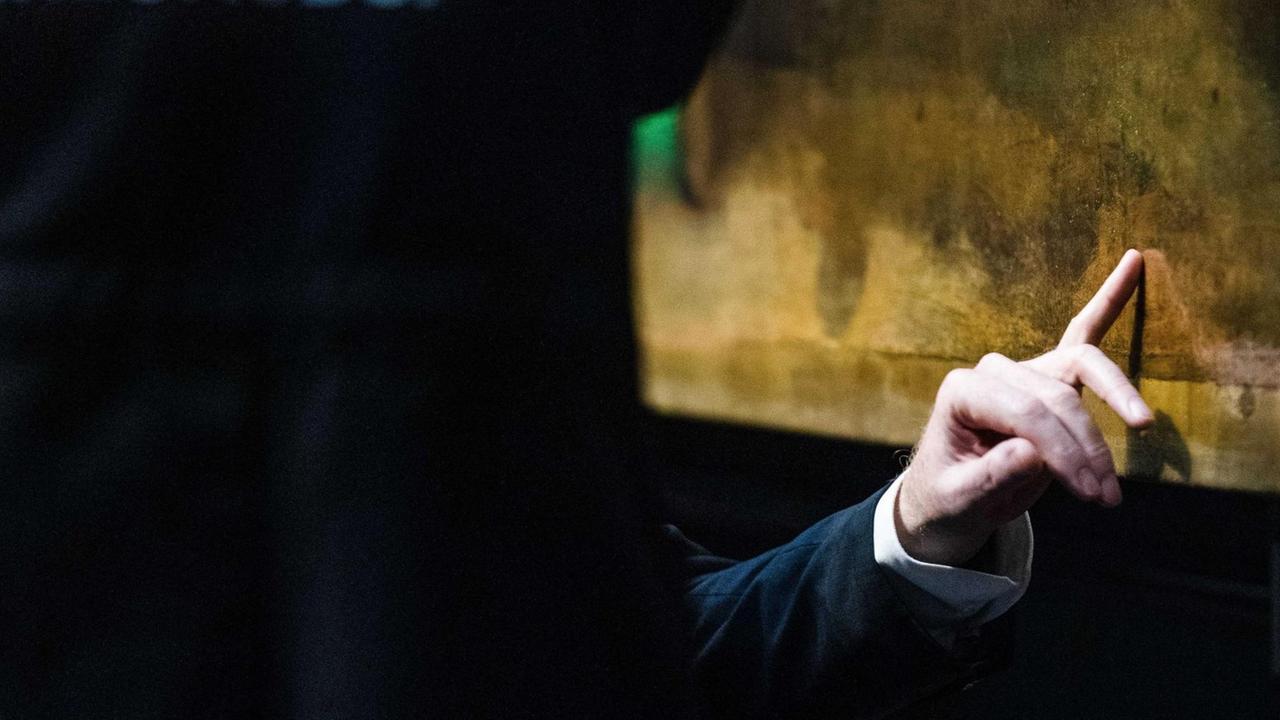 Detailaufnahme von einer Hand an einem Ölgemälde: Restauratoren arbeiten an Rembrandts "Nachtwache". Detailaufnahme von einer Hand an einem Ölgemälde: Restauratoren arbeiten an Rembrandts "Nachtwache".
