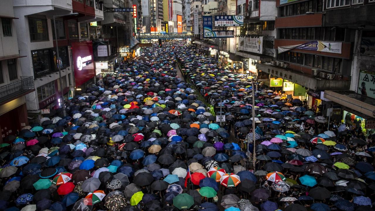 Ein Straßenzug in Hong Kong ist komplett voll mit Demonstrierenden, die Regenschirme tragen. Ein Straßenzug in Hong Kong ist komplett voll mit Demonstrierenden, die Regenschirme tragen.