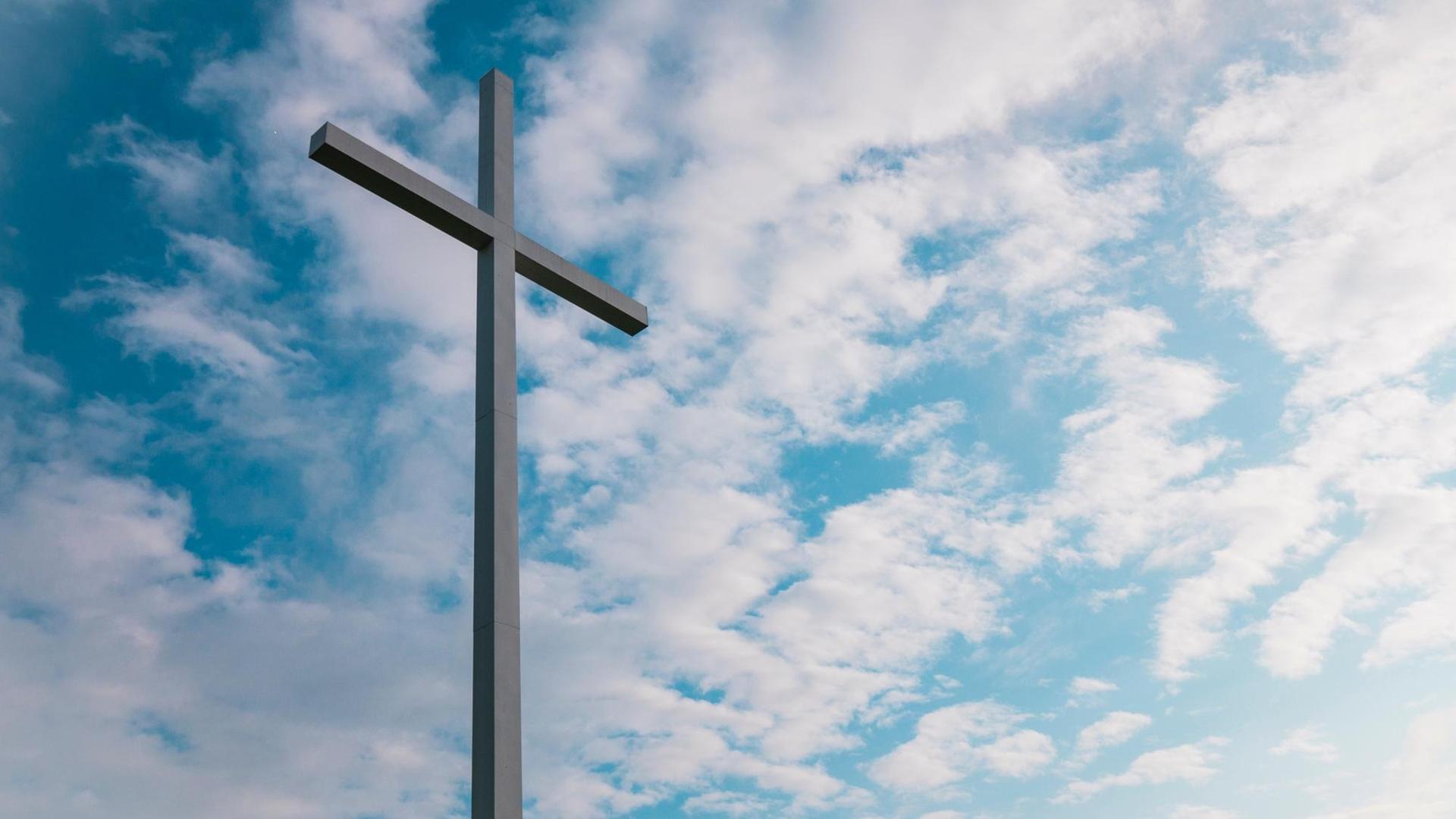 Ein schlichtes Kreuz vor blauem Himmel mit leichten Wolken