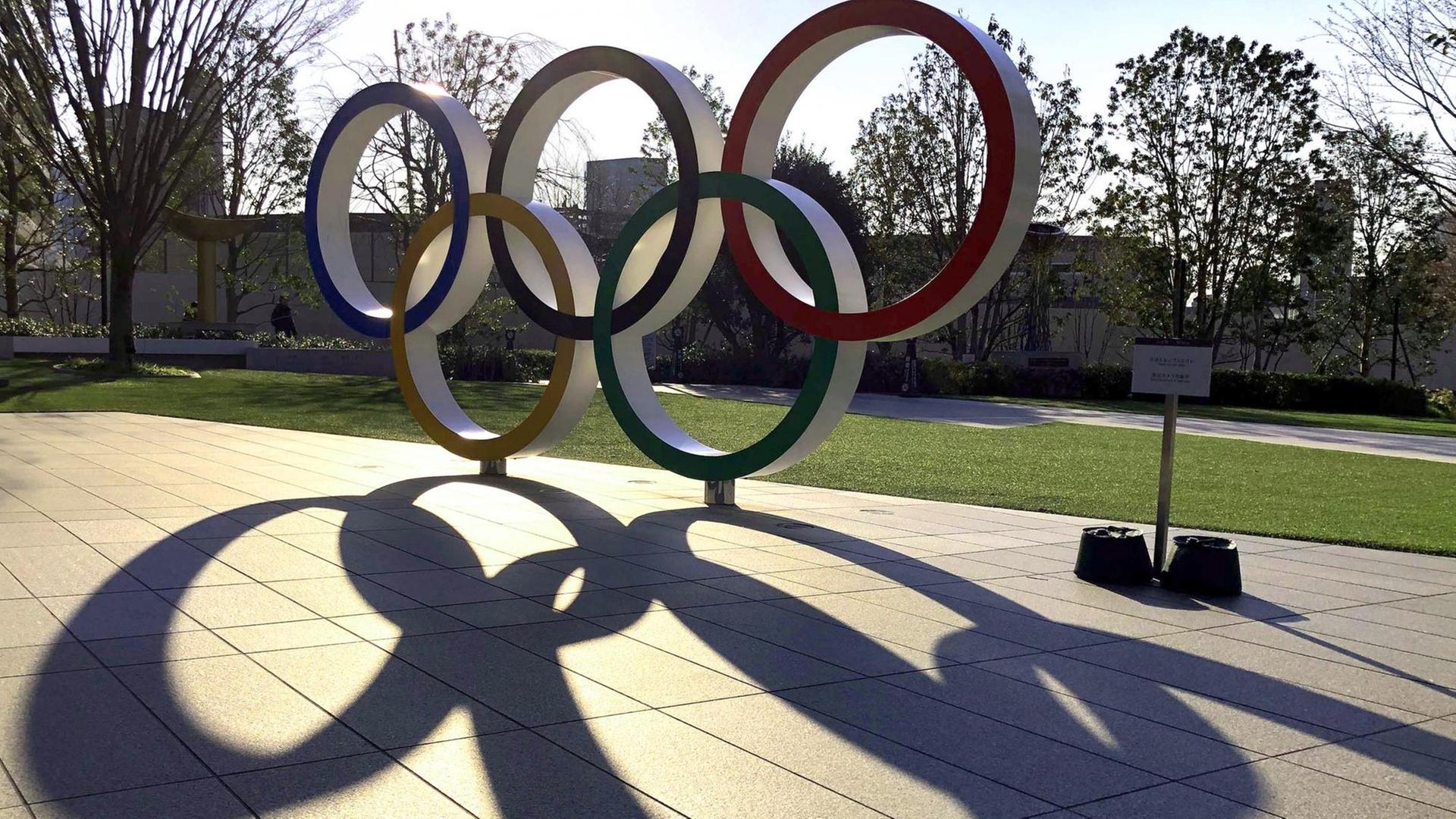 Eine Skulptur von den Olympischen Ringen steht an einer Straße.