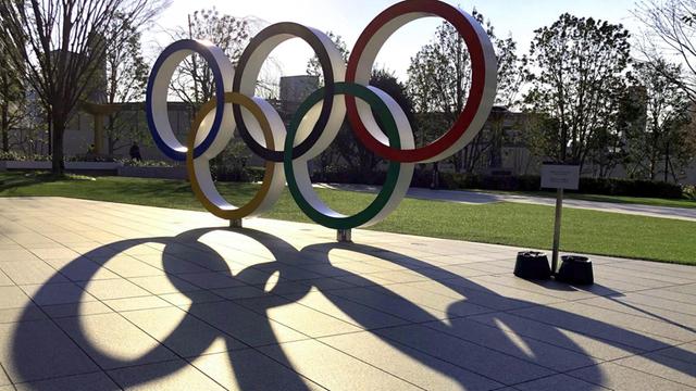 Eine aufgestellte Skulptur der Olympischen Ringe in einer Strasse von Tokio wirft lange Schatten