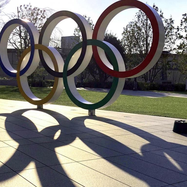 Eine aufgestellte Skulptur der Olympischen Ringe in einer Strasse von Tokio wirft lange Schatten
