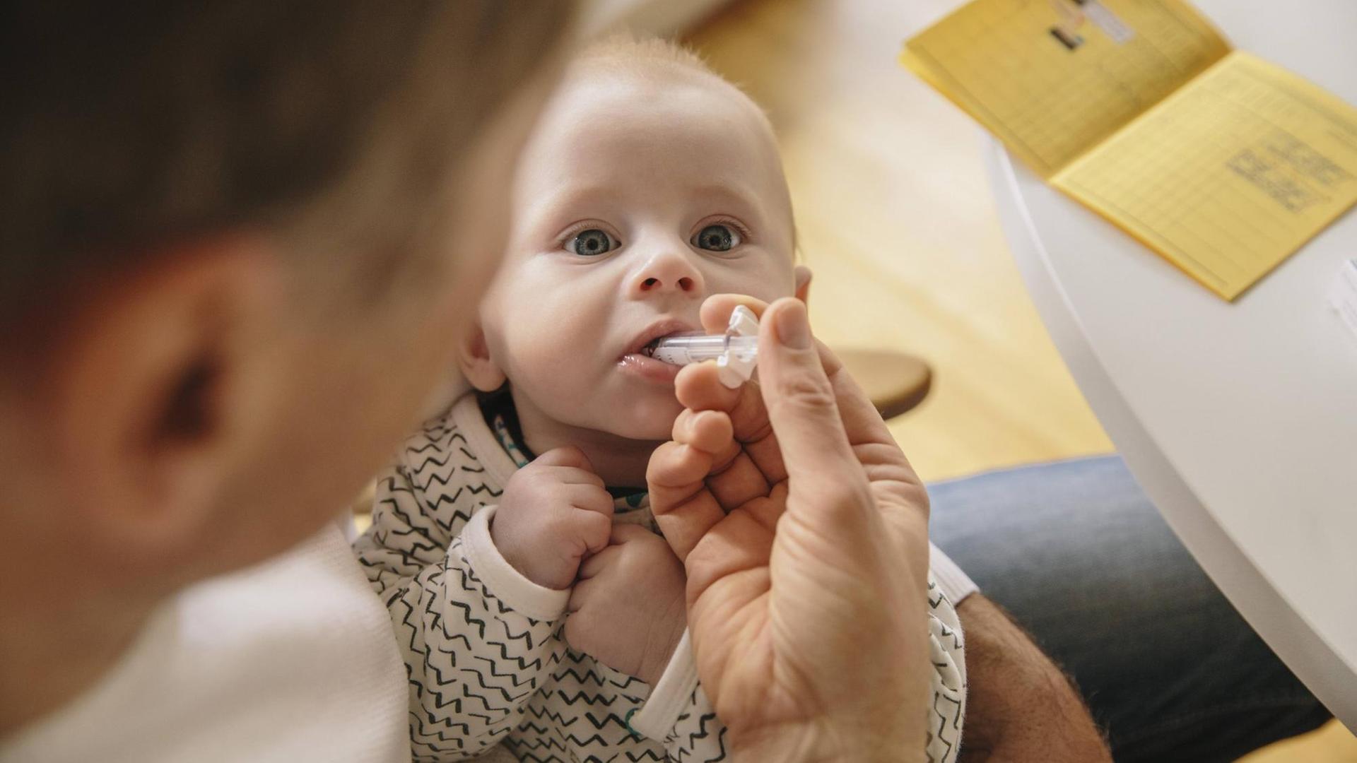 Ein drei Monate altes Baby erhält eine orale Impfung. Ein drei Monate altes Baby erhält eine orale Impfung.