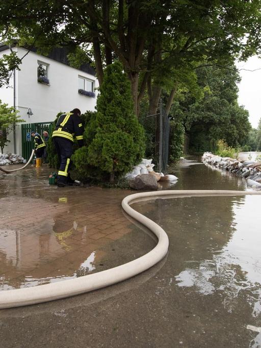 Einsatzkräfte der Feuerwehr pumpen am 27.07.2017 in Hildesheim (Niedersachsen) Wasser vom Tennisheim in den Fluss Innerste. Dauerregen hat im südlichen Niedersachsen in einigen Orten zu Überschwemmungen geführt.