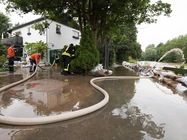 Einsatzkräfte der Feuerwehr pumpen am 27.07.2017 in Hildesheim (Niedersachsen) Wasser vom Tennisheim in den Fluss Innerste. Dauerregen hat im südlichen Niedersachsen in einigen Orten zu Überschwemmungen geführt.
