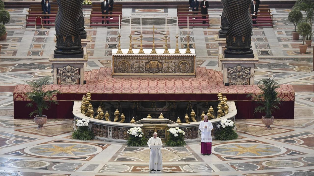 Papst Franziskus steht an einem Pult in einem fast menschenleeren Petersdom. Papst Franziskus steht an einem Pult in einem fast menschenleeren Petersdom.