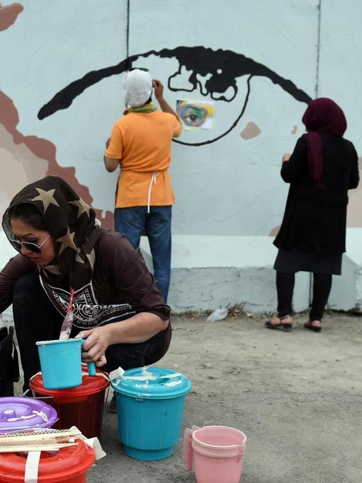 Auf dm Foto vom 21. Juli 2015 malen afghanische Künstlerinnen und Freiwillige das Motiv der Augen einer Frau auf eine Sperrmauer am Präsidentenpalast in Kabul.