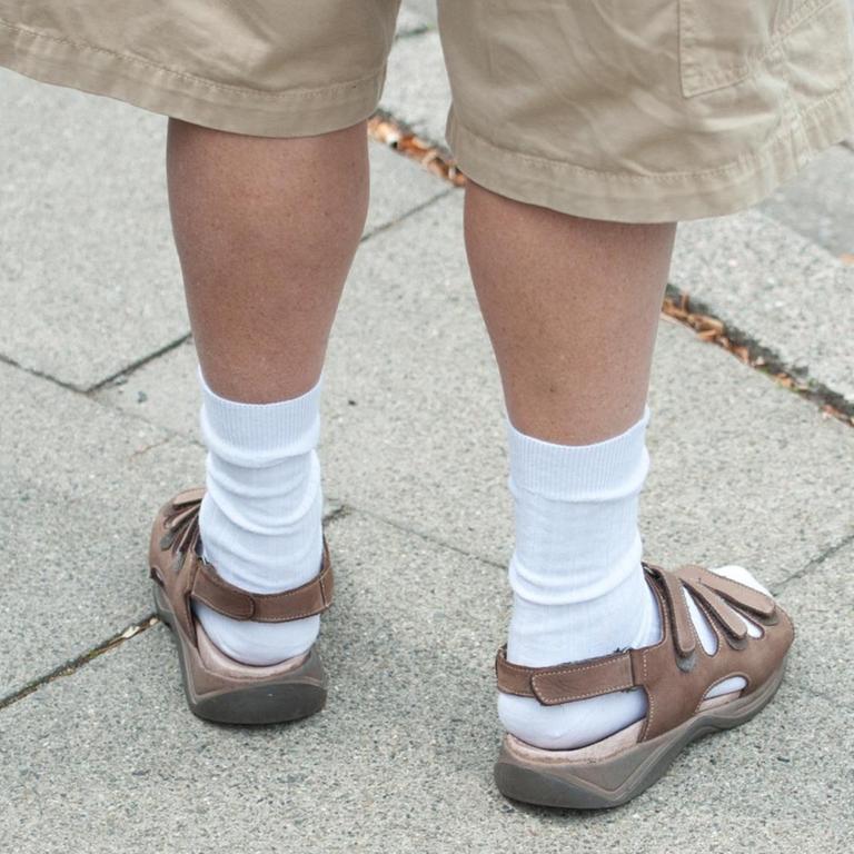 Ein Mann trägt kurze Hosen und Sandalen mit Socken.