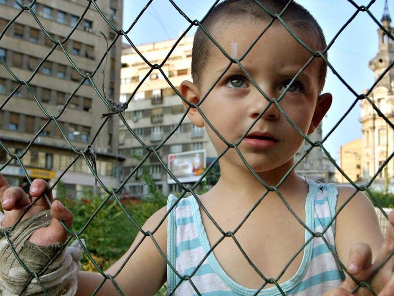 Ein rumänischer Junge schaut in Bukarest durch einen Maschendrahtzaun.