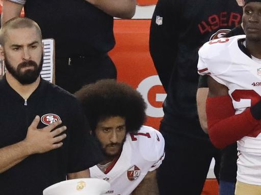 Der Quarterback der San Francisco 49ers, Colin Kaepernick (Mitte), kniet beim Abspielen der Nationalhymne.
