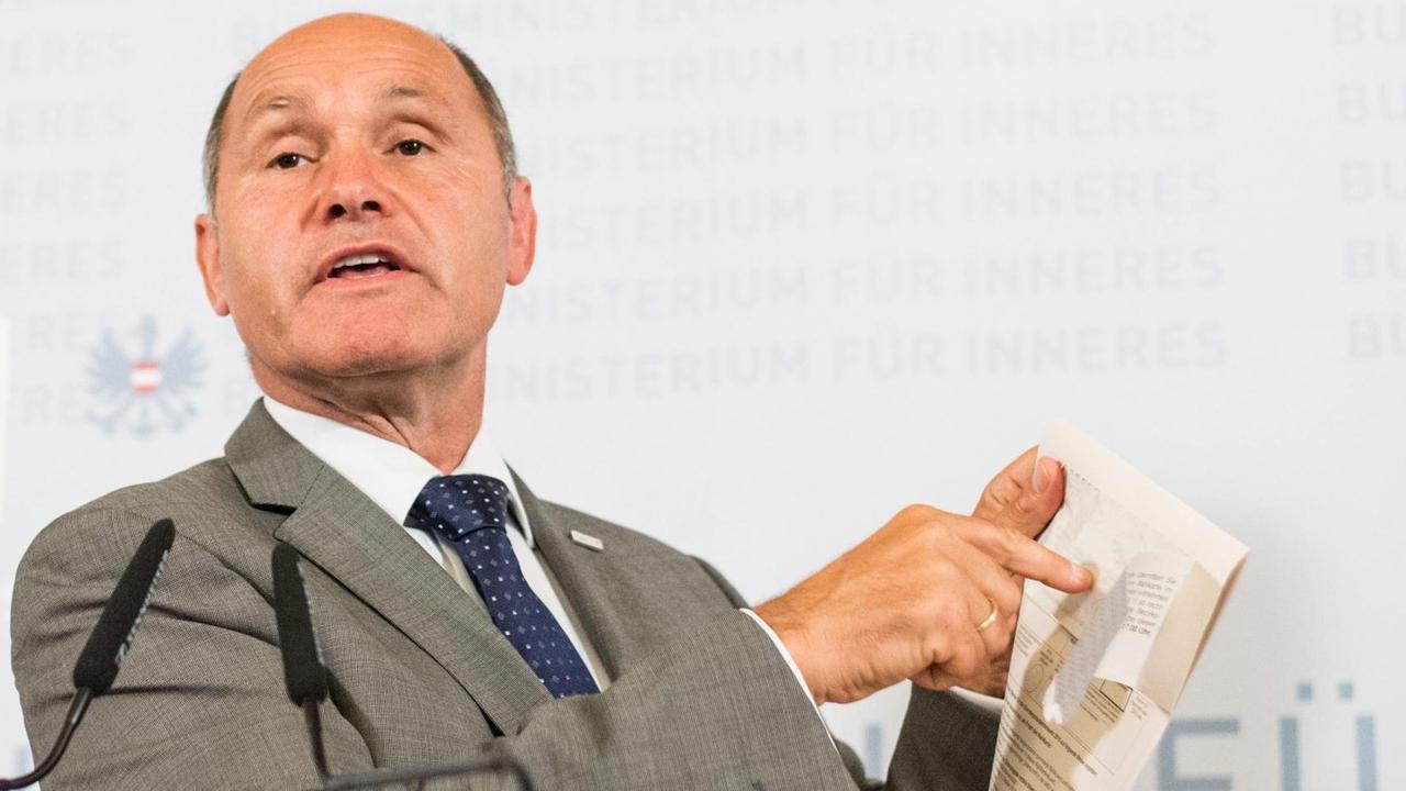 Sobotka hinter einem Rednerpult. Er zeigt auf die Stelle des Wahlumschlags, wo der Kleber fehlerhaft ist. Sobotka hinter einem Rednerpult. Er zeigt auf die Stelle des Wahlumschlags, wo der Kleber fehlerhaft ist.