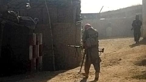 Taliban-Kämpfer mit Waffe geht auf einer Straße.
