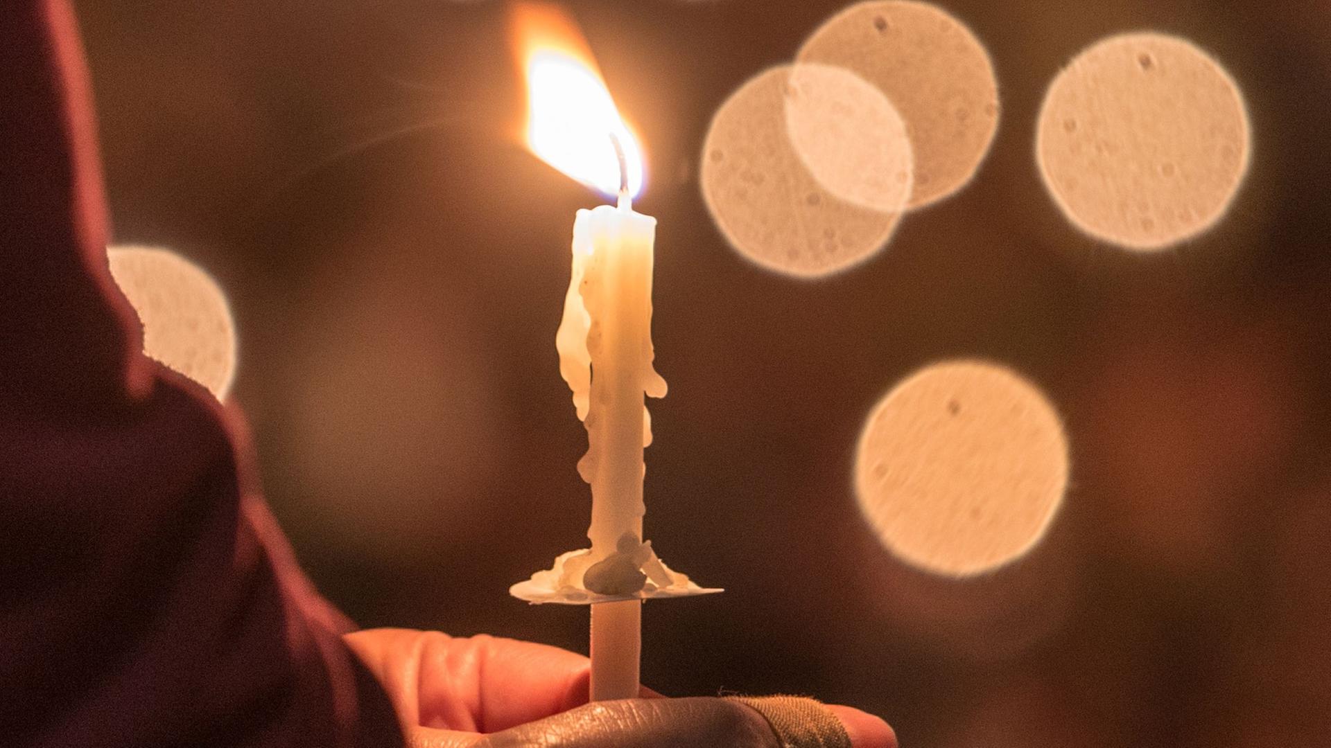 Eine Gläubige hält eine brennende Kerze. Eine Gläubige hält eine brennende Kerze.