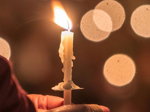 Eine Gläubige hält eine brennende Kerze.