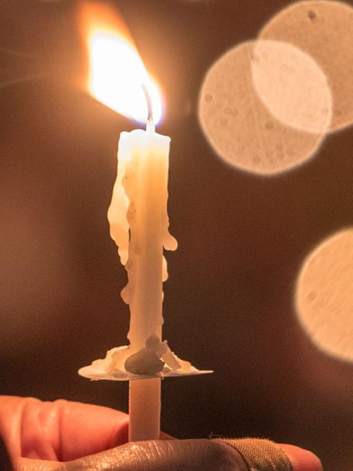 Eine Gläubige hält eine brennende Kerze.