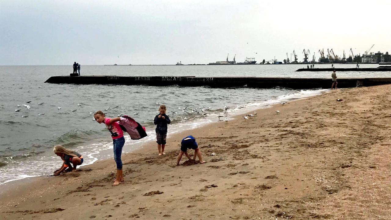 Menschen am Strand von Mariupol, eine Industriestadt am Asowschen Meer, in der Ukraine Menschen am Strand von Mariupol, eine Industriestadt am Asowschen Meer, in der Ukraine