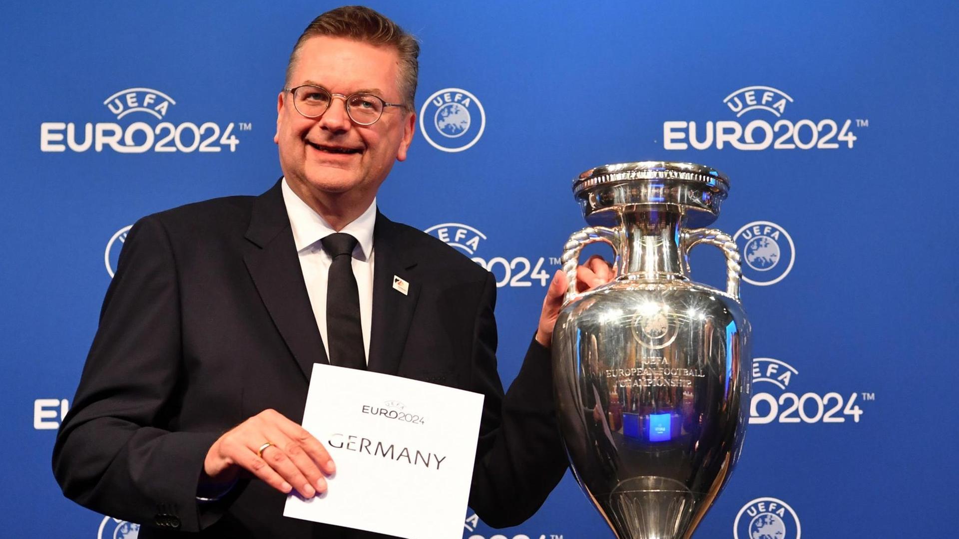 DFB-Präsident Reinhard Grindel von der deutschen Delegation hält einen Zettel mit "Germany" neben dem EM-Pokal während der Bekanntgabe-Zeremonie zur Ausrichtung der Fußball-Europameisterschaft 2024. DFB-Präsident Reinhard Grindel von der deutschen Delegation hält einen Zettel mit "Germany" neben dem EM-Pokal während der Bekanntgabe-Zeremonie zur Ausrichtung der Fußball-Europameisterschaft 2024.