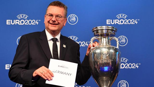 DFB-Präsident Reinhard Grindel von der deutschen Delegation hält einen Zettel mit "Germany" neben dem EM-Pokal während der Bekanntgabe-Zeremonie zur Ausrichtung der Fußball-Europameisterschaft 2024.