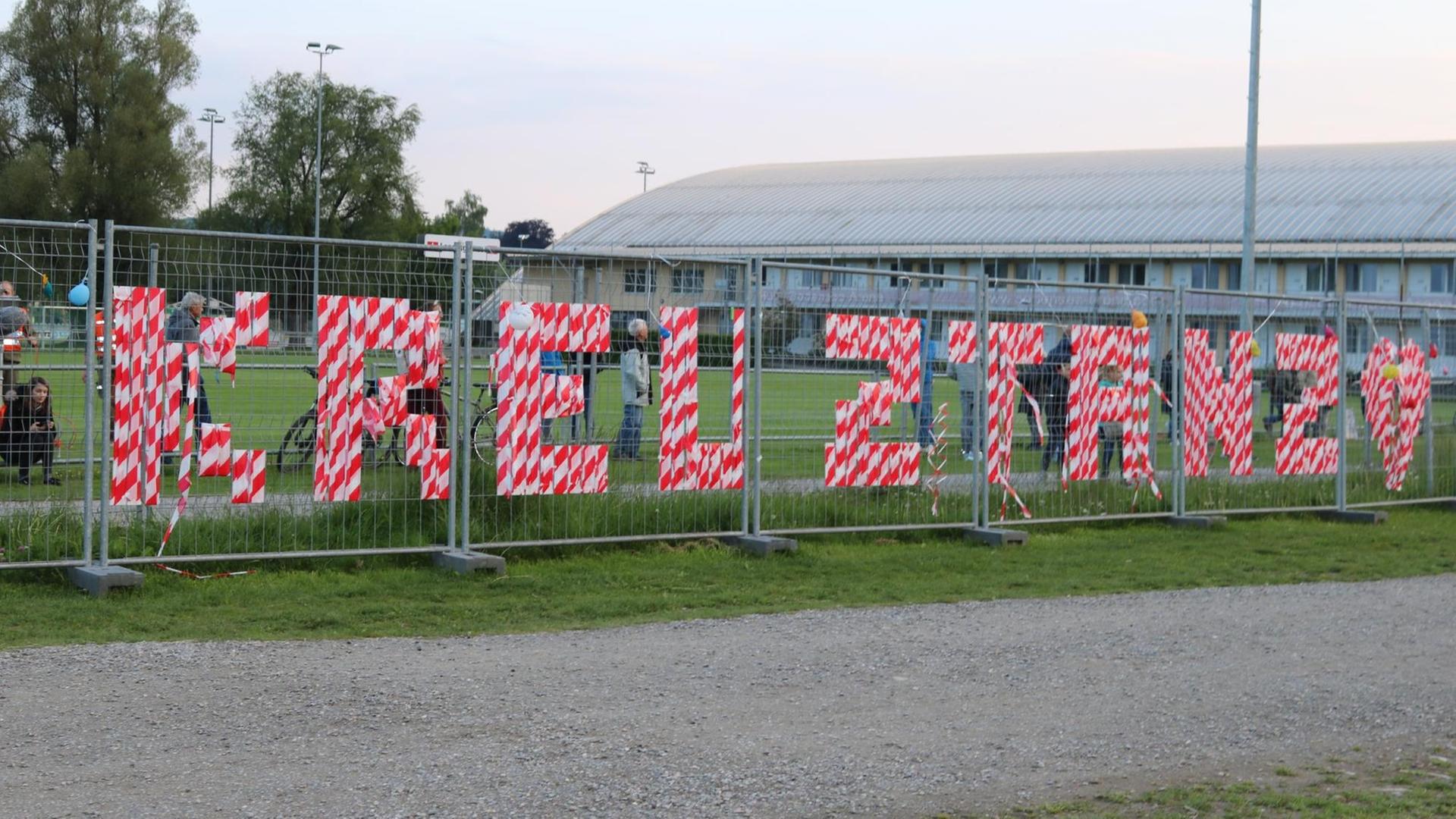 Ein Zaun steht auf einer Wiese. Mit rot-weißem Folienband sind die Buchstaben für Kreuz-Stanz eingewoben. Ein Zaun steht auf einer Wiese. Mit rot-weißem Folienband sind die Buchstaben für Kreuz-Stanz eingewoben.