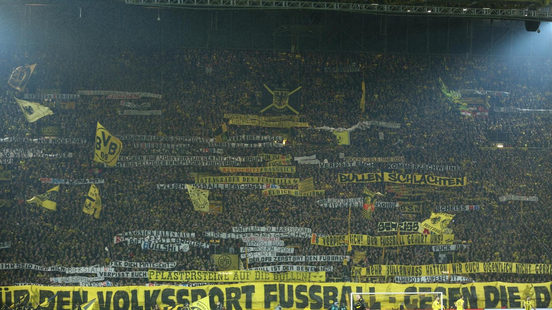 Dortmunder Fans entrollen (04.02.17) vor Spielbeginn auf der Südtribüne Spruchbänder, mit denen sie den RB Leipzig kritisieren.