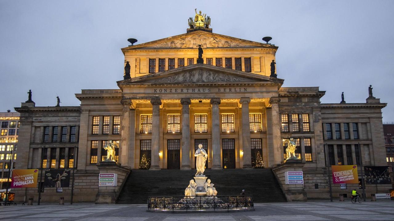 Blick auf das festliche erleuchtete, historische Konzerthaus mit Schillerdenkmal in der Dämmerung.