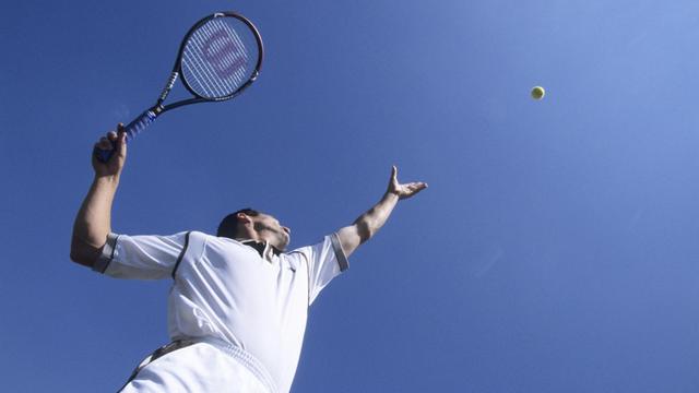 Ein Tennisspieler macht einen Aufschlag.
