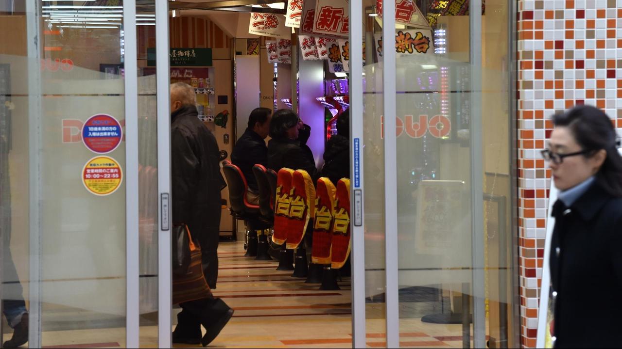 Ene Frau läuft an einer Spielhalle in Tokio vorbei, in dem vor allem das japanische Automaten-Glücksspiel Pachinko angeboten wird