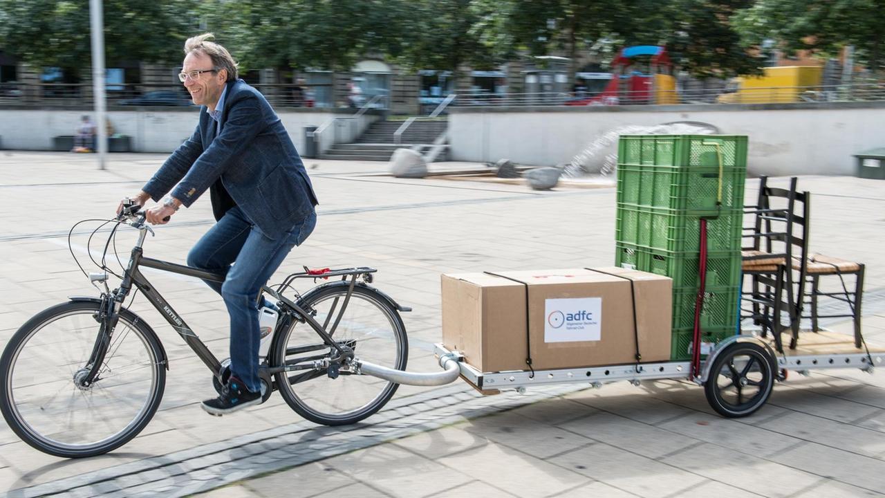Der Verwaltungsbürgermeister der Stadt Stuttgart, Werner Wölfle (Bündnis 90/Die Grünen) fährt am 03.09.2015 auf dem Marienplatz in Stuttgart (Baden-Württemberg) mit einem Fahrrad, an dem ein Schwerlasthänger angebracht ist. Der Anhänger der amerikanischen Firma Firma Bikes at Work kann Lasten bis zu 150 Kg Tragen und muss mit einer Speziellen Kupplung am Fahrrad angebracht werden. Bei der verkehrspolitischen Sommerradtour des Allgemeinen Deutschen Fahrrad-Clubs (ADFC) Baden-Württemberg soll die Vielseitigkeit der Lastenräder demonstriert werden. Foto: Wolfram Kastl/dpa | Verwendung weltweit Der Verwaltungsbürgermeister der Stadt Stuttgart, Werner Wölfle (Bündnis 90/Die Grünen) fährt am 03.09.2015 auf dem Marienplatz in Stuttgart (Baden-Württemberg) mit einem Fahrrad, an dem ein Schwerlasthänger angebracht ist. Der Anhänger der amerikanischen Firma Firma Bikes at Work kann Lasten bis zu 150 Kg Tragen und muss mit einer Speziellen Kupplung am Fahrrad angebracht werden. Bei der verkehrspolitischen Sommerradtour des Allgemeinen Deutschen Fahrrad-Clubs (ADFC) Baden-Württemberg soll die Vielseitigkeit der Lastenräder demonstriert werden. Foto: Wolfram Kastl/dpa | Verwendung weltweit