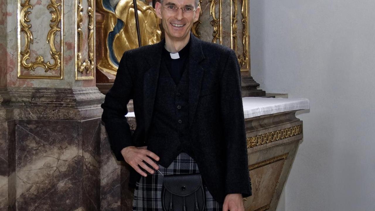 Pfarrvikar Wolfgang Rothe posiert im Schottenrock vor barockem Altar Pfarrvikar Wolfgang Rothe posiert im Schottenrock vor barockem Altar
