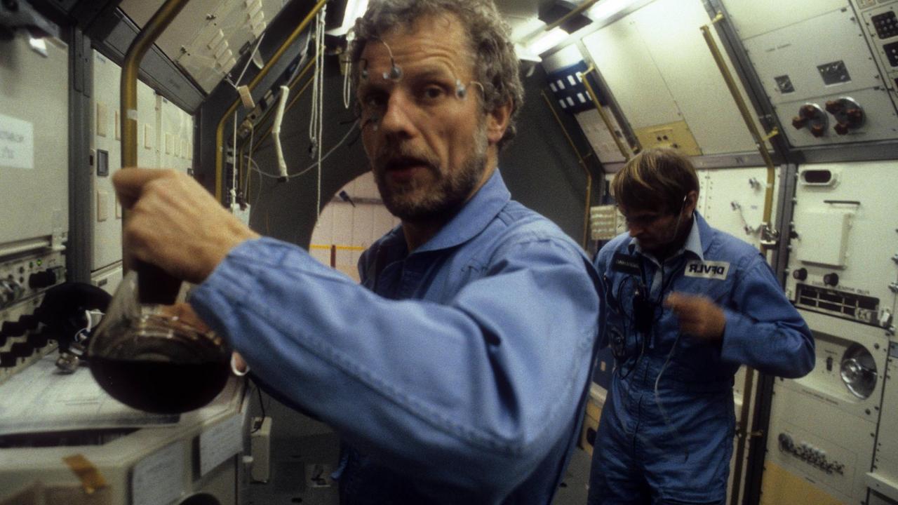 Astronauten Reinhard Furrer und Ernst Messerschmid verkabelt im inneren einer Raumkapsel. Astronauten Reinhard Furrer und Ernst Messerschmid verkabelt im inneren einer Raumkapsel.