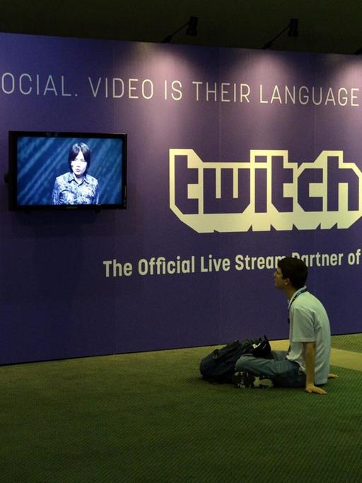Ein junger Mann sitzt vor Bildschirmen der Streamingplatform Twitch.