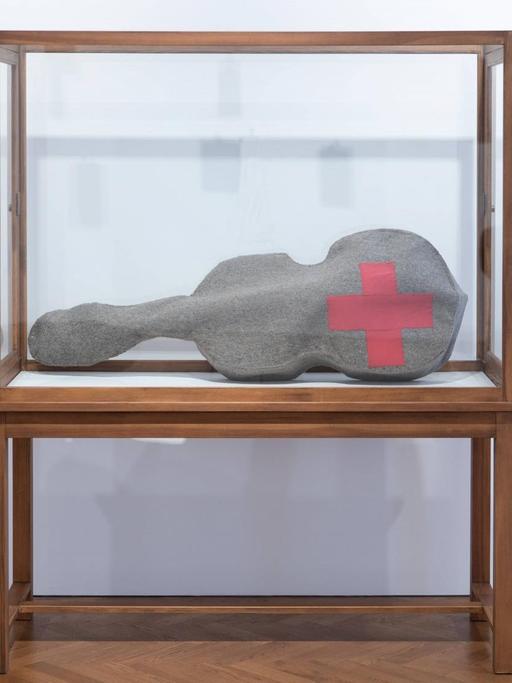 Beuys Arbeit 'Infiltration - Homogen für Cello' besteht aus einer gefilzten Cello-Tasche mit einem roten Kreuz. Hier zu sehen in einer Glasvitrine während der Ausstellung "The Stag Monuments" in der Galerie Thaddaeus Ropac in London, kuratiert von Norman Rosenthal.
