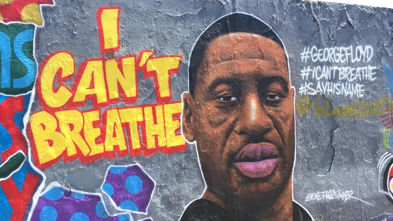 Ein Porträt von George Floyd gemalt auf eine bunte Wand mit den Buchstaben "I can't breathe. Ein Porträt von George Floyd gemalt auf eine bunte Wand mit den Buchstaben "I can't breathe.