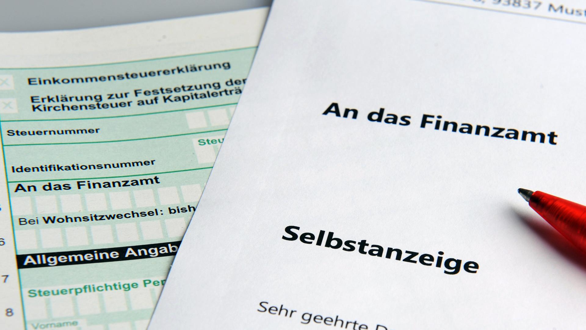 Im Bild ist links ein Steuererklärungsformular und darüber liegend rechts ein weißes Blatt mit dem Titel "Selbstanzeige" zu sehen. Im Bild ist links ein Steuererklärungsformular und darüber liegend rechts ein weißes Blatt mit dem Titel "Selbstanzeige" zu sehen.