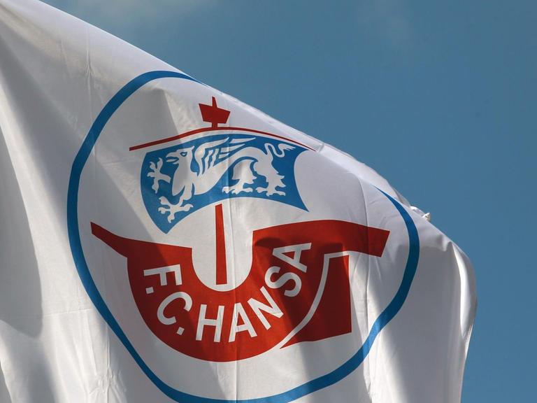 Vor dem Stadion in Rostock weht eine Fahne des FC Hansa Rostock im schwachen Wind.