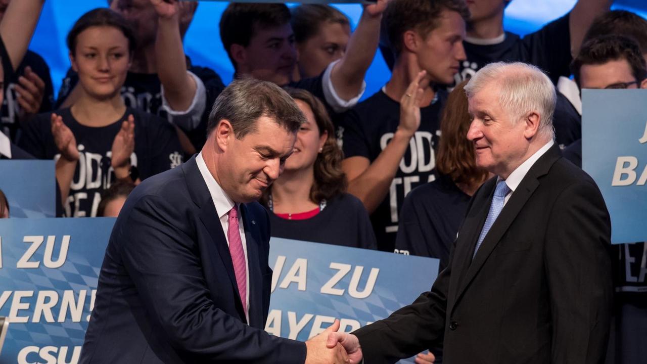 Markus Söder (l), Ministerpräsident von Bayern, und Horst Seehofer (beide CSU), Bundesminister für Inneres, stehen nach der Rede von Söder beim CSU-Parteitag im Postpalast auf der Bühne und geben sich die Hand (15.9.2018).