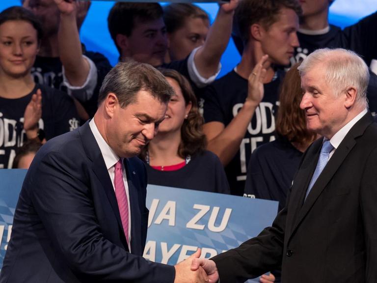 Markus Söder (l), Ministerpräsident von Bayern, und Horst Seehofer (beide CSU), Bundesminister für Inneres, stehen nach der Rede von Söder beim CSU-Parteitag im Postpalast auf der Bühne und geben sich die Hand (15.9.2018).